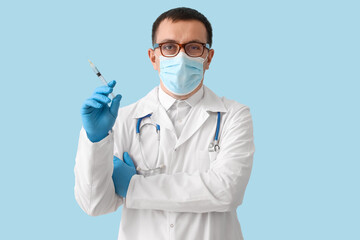 Doctor with syringe on light blue background