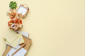 Set of different stationery with alarm clock on color background