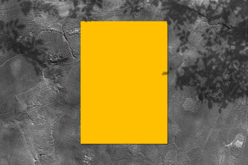 Empty yellow square poster mockup with light shadow on black concrete wall background.