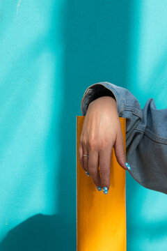 A Female Hand With Blue Painted Acrylic Nails Resting On A Pipe
