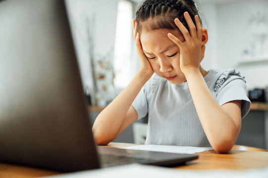 Schoolgirl studying with video online lesson and overwhelmed 