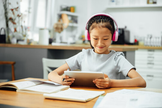 Young girl doing homework with headphone and digital tablet