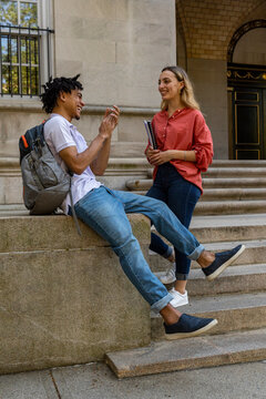 Two cute Friends University Students in conversation and boy claps