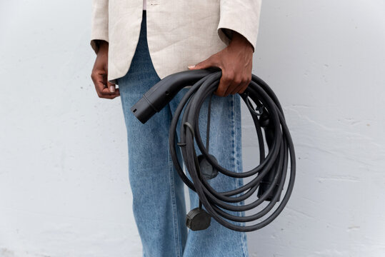 Anonymous black man with electric car cable