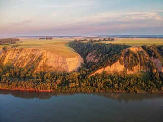 Clay coast with groves of birch trees, soil erosion, sunset clouds and the Ob riverbed