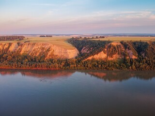 Clay coast with groves of birch trees, soil erosion, sunset clouds and the Ob riverbed