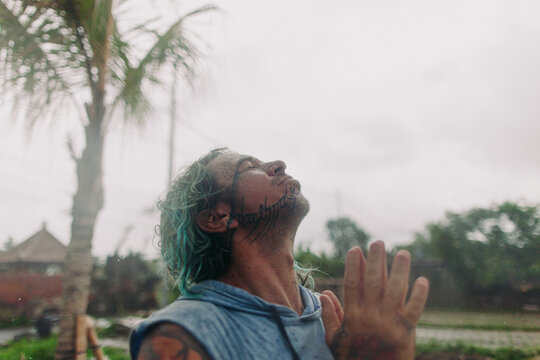 portrait of a man under the tropic rain catching the water drops 
