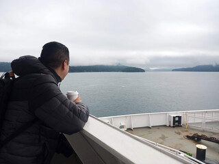 Latino adult man travels by boat watching the cold sea, rests from his job in Canada and lives the...