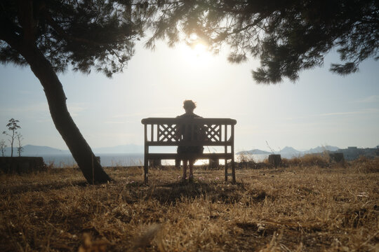 Woman resting on a bench among the trees.