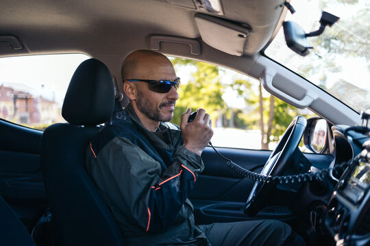 Forest service man in uniform talking on walkie talkie in car
