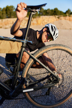 Male cyclist fixing bike in desert