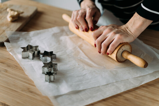 Woman rolls out the dough with a rolling pin.