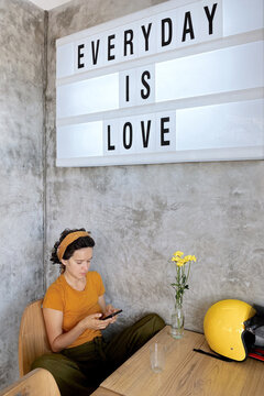 Young woman uses smartphone in cafe