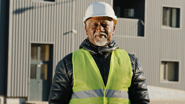 Close-up Elderly African American Man Construction Worker Standing In Protective Helmet Uniform Outdoors Confident Workman Crossed Arms Across Chest Successful Builder Contractor Looking Camera Posing