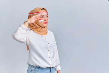 Happy young Asian woman making salute gesture isolated on white background. Indonesian independence day concept