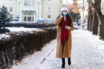 beautiful girl in a hurry to work walking on the snowy streets of the city and talking on the phone