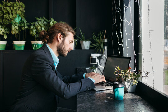 Modern young man uses laptop in informal office.