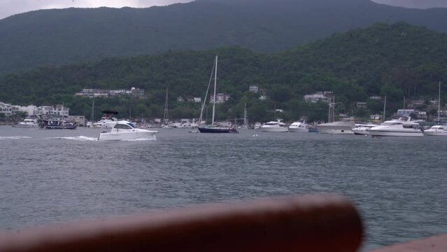 Beautiful footage of a boat moving on a calm lake on a cloudy day with green hills in the background