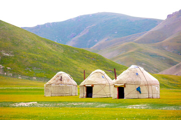 Yurt. National old house of the peoples of Kyrgyzstan and Asian countries. national housing. Yurts on the background of green meadows and highlands. Yurt camp for tourists. - obrazy, fototapety, plakaty