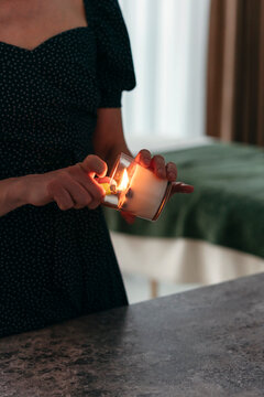 Faceless person lights candle.