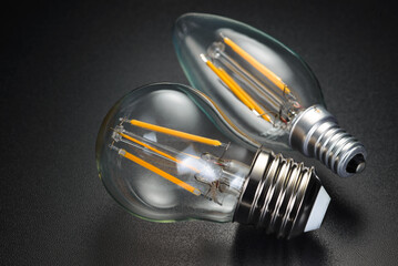 LED filament bulbs on black background. - obrazy, fototapety, plakaty