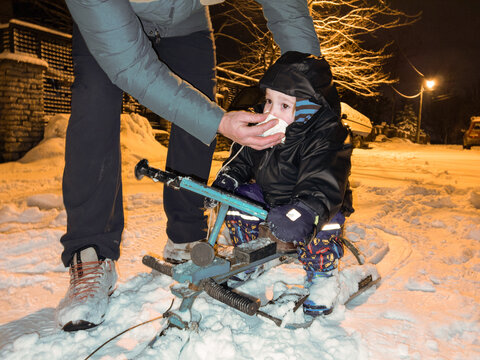 A parent wipes his kid's mucus during the winter, outdoor