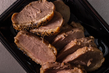 Takeout smoked duck breast slices in the food tray. Closeup image.