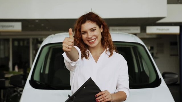 Attractive woman consultant of car center standing near car.Auto rental or sales concept