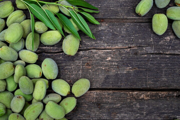 Green almonds background   fresh raw unripe wooden rustic table blurred garden background leaves, Top view concept with copy space shell  tree branch pattern texture