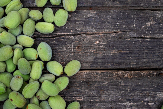 Green almonds background   fresh raw unripe wooden rustic table blurred garden background leaves, Top view concept with copy space shell  tree branch pattern texture