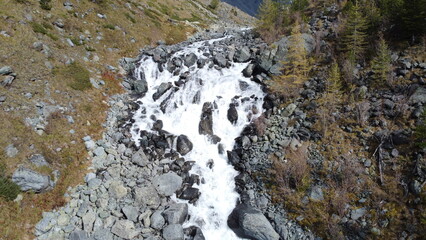 Mountain flowing stream and waterfall in the forest. Picturesque earial drone landscape view. Altai mountains, Russia