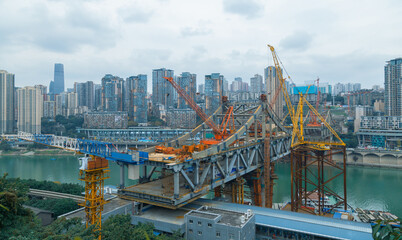 This is Chongqing, China, where a bridge is being built over a large river. This bridge will connect the two sides of the river and make the traffic more convenient. 