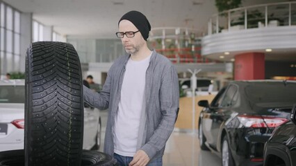 A man chooses tires for his car. Buying the right tires for the wheels.