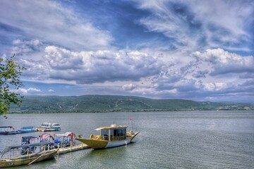 Naklejka premium beautiful view of lake uluabat and name of city golyazi (Gölyazı), ancient boat on lake under cloudscape.