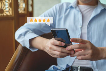 Customer hand press on smartphone screen with gold five star rating feedback icon excellent rank level for giving best score point to review the service , ranking experience, evaluate quality.