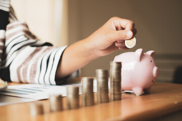 Woman's hand. putting coins in the piggy bank with coins, saving money with coins, stepping into a...