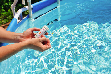 Checking the water quality of a pool with the help of a test strip with PH value, chlorine and algaecide
