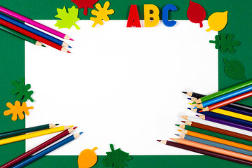 Pencils, paper, letters, decorative leaves on a green background. Office desk with copy space. Banner, background Back to school concept. School supplies, creative flat lay desk.