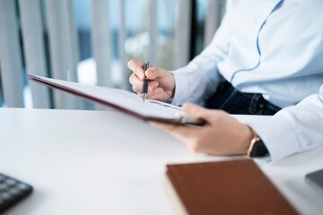 Portrait of  Asian Business woman working from office taking reading and writing notes in note pad...