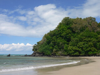 Beach scene with sand, the ocean, and a cliff at Cape Tribulation in Far North Queensland, Australia