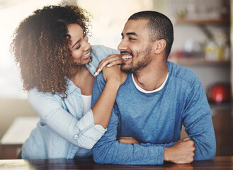 Loving, caring and smiling couple in a kitchen at home. Man and woman looking at each other in love, joy and happiness. Young romantic people having an affectionate moment together indoors