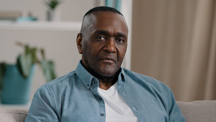 Obraz premium Upset male Serious african american mature professional man looking at camera successful confident handsome smart adult entrepreneur manager freelancer posing at home close-up business portrait