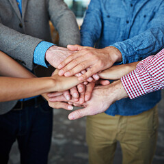 Teamwork, collaboration and support while putting hands together in an office for motivation and unity amongst colleagues. Group of businesspeople standing together in a huddle during team building