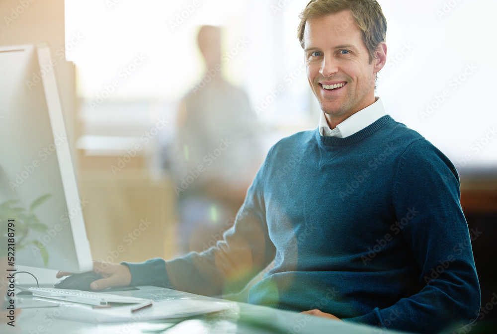 Poster Portrait of a happy, excited and smiling businessman working on computer at work. Cheerful executive professional with a smile sitting at desktop in modern casual office with colleague in the back.