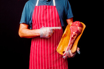Butcher holding wooden board with raw tomahawk steak on the bone and black background. Prime cut of...