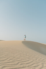 Fototapeta na wymiar junger mann stehend auf einer Düne in der Wüste im Abendlicht Sonnenschein