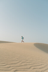 Fototapeta na wymiar Junger Mann rennt durch die Wüste die Dünen entlang im Abendlicht