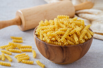 Raw fusilli pasta in wooden bowl.