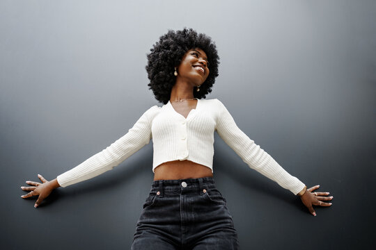 Fashionable young beautiful woman with afro hairstyle posing on the black wall