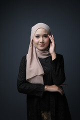 Portrait of a female  wearing a hijab, a form of lifestyle garments for Muslim women, isolated on a dark background. Eid festive and hijab fashion concept